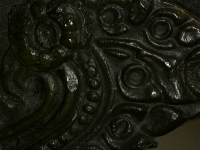 Mikroskopische Analyse der Gussqualität einer thailändischen Bronze. Die Aufnahme zeigt die feine Oberflächenstruktur des Bronzegusses, mineralische Patina-Einschlüsse und das Fehlen von Gussfehlern, Lot 445, 1stbuddha.